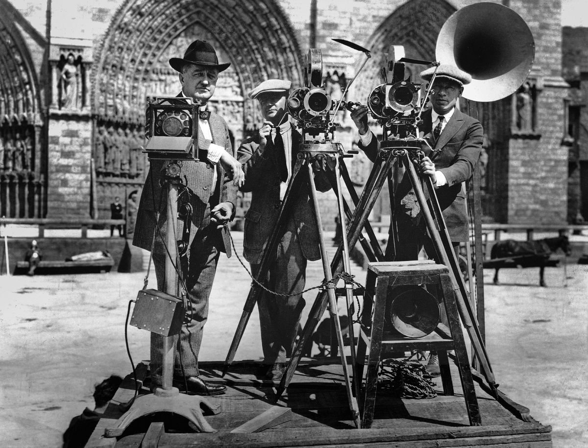 Wallace Worsley, left, uses the first movie set public address system. Bell & Howell cameras are operated by Robert S. Newhard, ASC, shooting the domestic negative, and Harry McGuire, making the foreign negative.