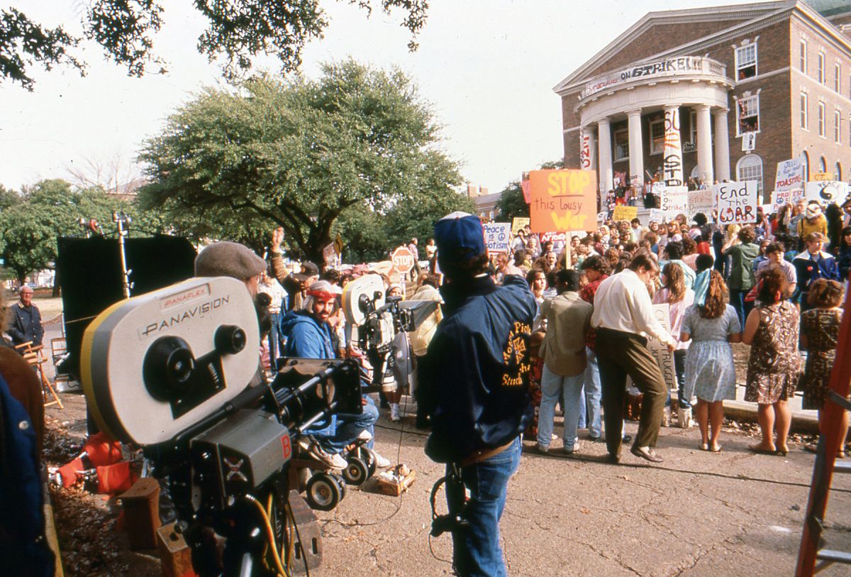 Richardson (seated, wearing red headband) prepares to roll on a crowd scene for Born on the Fourth of July (1989).