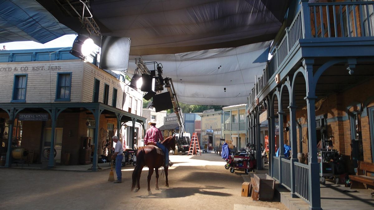 Charcoal Grid Cloth hangs over the Universal backlot’s Western Street set “to eliminate frontlight on background action and buildings,” Kincaid explains. “[K 5600] 18K Alphas were cantilevered on truss mounted to condors to illuminate the interior of the saloon. Flags rigged to the truss isolated each of the HMIs to a specific window so the separate sources weren’t revealed in the atmospheric smoke.”
