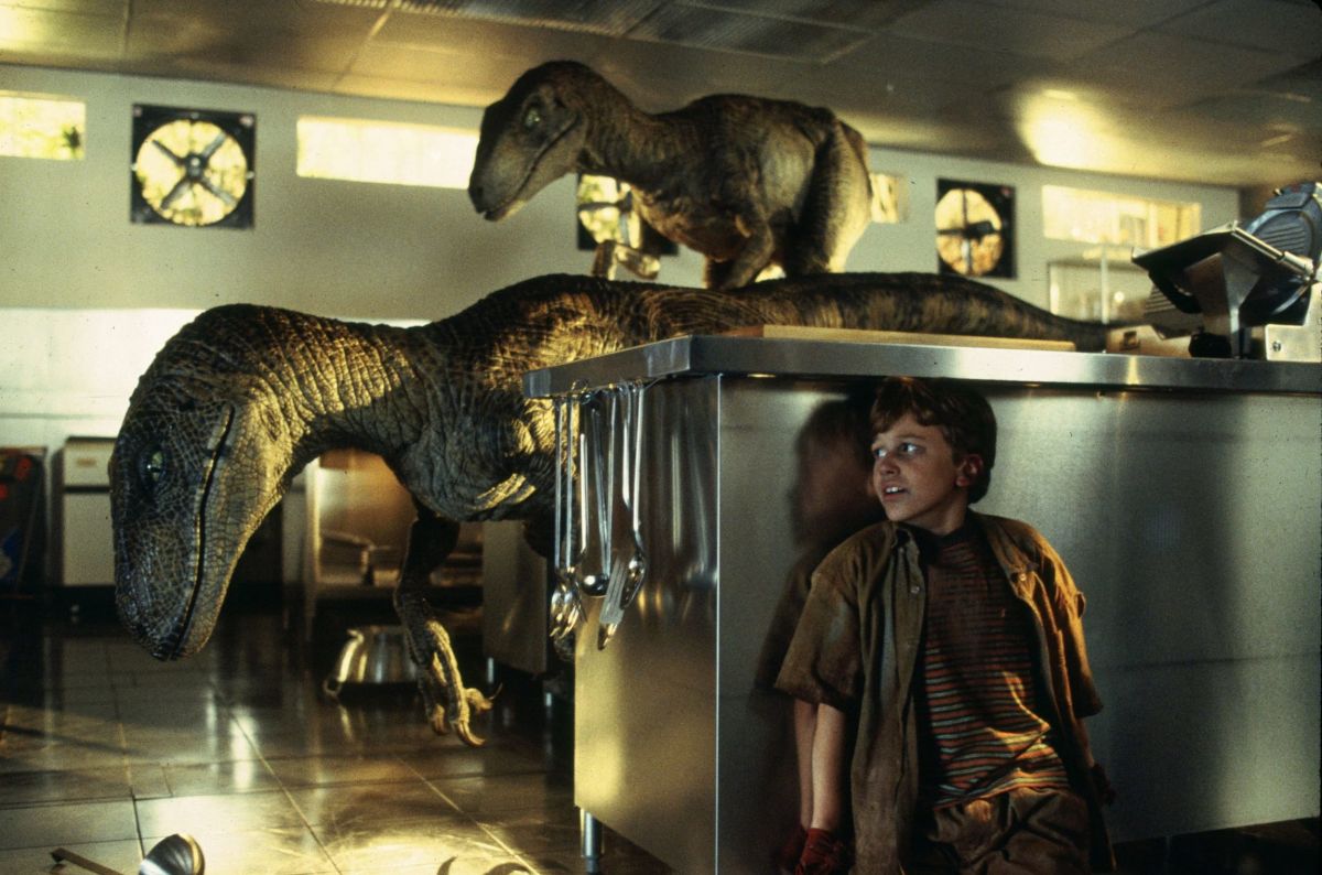 Tim (Joseph Mazzello) hides from a pair of raptors in the industrial-looking kitchen.