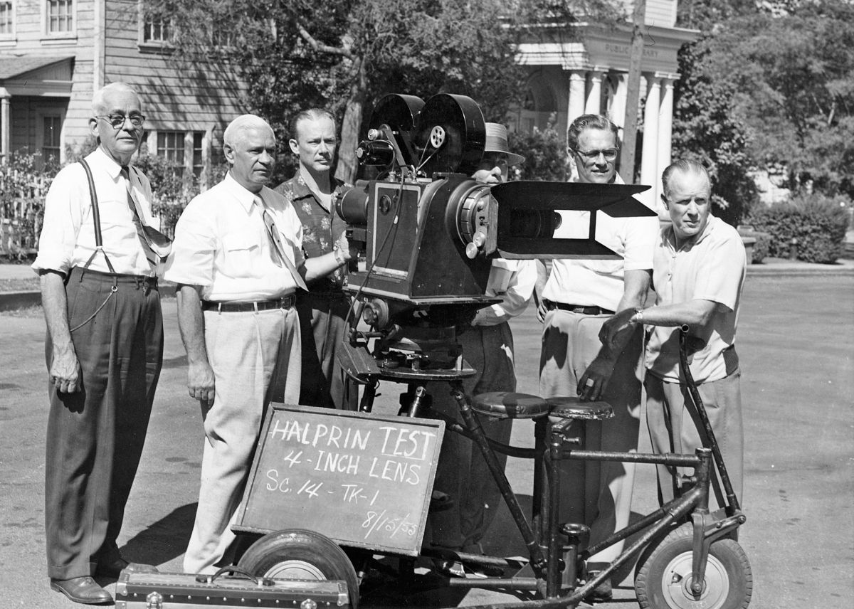Following decades of work behind the camera, Sol Halprin, ASC (seen second from left ) became 20th Century Fox’s executive director of photography. Him, studio engineer Grover Laube (far left ) and chief research engineer Earl Sponable (not in this photo), developed the widescreen CinemaScope 55 system being tested on this summer day in 1955. The camera is a Fox 4x55, a Mitchell 70mm camera built in the 1930s and converted by the Fox camera department to handle a 55.625mm wide, 8-perf-high negative. Bausch & Lomb made custom anamorphic lenses for the unique format. Unfortunately, tests with CinemaScope 55 — used to shoot the lavish musicals The King and I and Carousel (both released in 1956) — convinced the studio that the audience did not perceive the promised quality diﬀerence, meaning the added expense in production and post was not worthwhile. As a result, Fox abandoned CinemaScope 55 in favor of the more-established 65mm Todd-AO system.