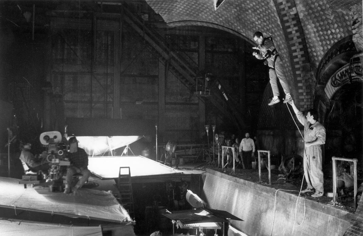 Chapman is suspended to check his light on a tricky shot while filming Ghostbusters II (1989), directed by Ivan Reitman.